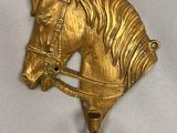 gold colored horse head hook on a white background