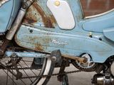 a close up of a blue motorcycle with rust on it