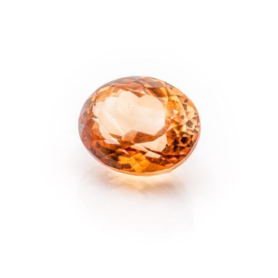 a close up of an orange sapphire stone on a white surface