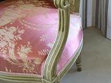 a pink and gold chair in front of a window