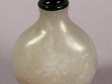 a white glass bottle with a green lid sitting on a table