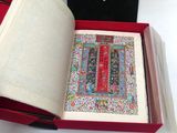 un livre ouvert dans une boîte rouge posée sur une table blanche