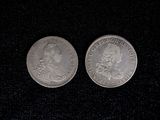 two silver coins sitting on top of a black surface