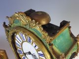 a green and gold clock that is on a table