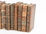 several old books are stacked on top of each other on a white surface