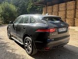 a black car that is parked in front of a hay bale
