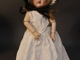 a doll that is wearing a white dress and a hat