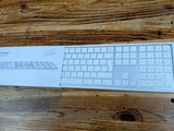 a white keyboard sitting on top of a wooden table
