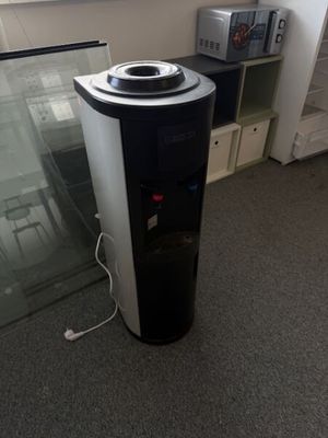 a black and white water dispenser next to a glass door