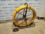 a yellow hose on a cart in front of a wall