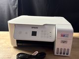 a white printer sitting on top of a wooden table next to a charger