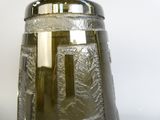 a green glass vase with a silver lid on a table