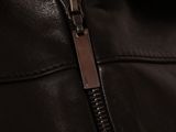 close up of a zipper on a leather jacket with a black background