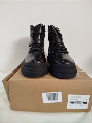 La boîte contient une paire de chaussures noires posées sur un fond blanc.