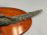a bronze sculpture of a bird on a wooden plate