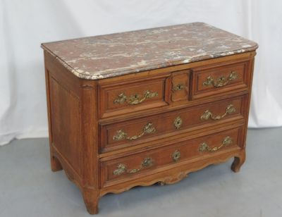une commode au plateau en marbre posée sur un sol gris
