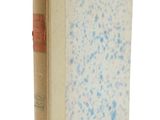 un vieux livre posé sur une surface blanche parsemée de taches bleues
