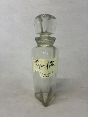une petite bouteille en verre sur laquelle est collé un autocollant