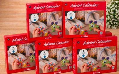 quatre calendriers de l'Avent pour enfants, dans des boîtes rouges, posés sur une table en bois