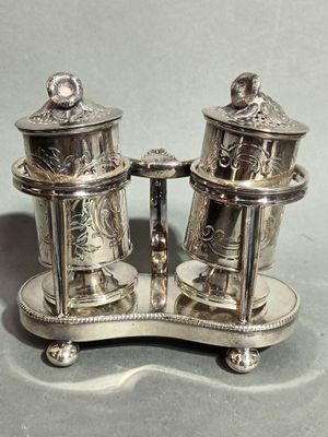 a silver salt and pepper shaker set on a stand