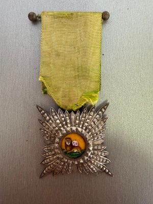 silver medal with a yellow ribbon on top of a metal surface