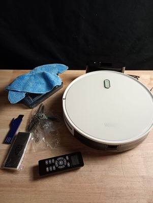 un robot blanc posé sur une table, à côté d'une télécommande