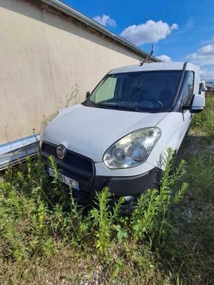 une camionnette blanche garée à côté d'un immeuble, dans un espace vert