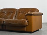 a brown leather couch sitting in a room with a white wall