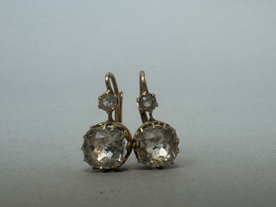 une paire de boucles d'oreilles en diamant posées sur une surface grise