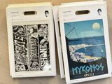 two boxes of skateboard stickers sitting on a wooden surface