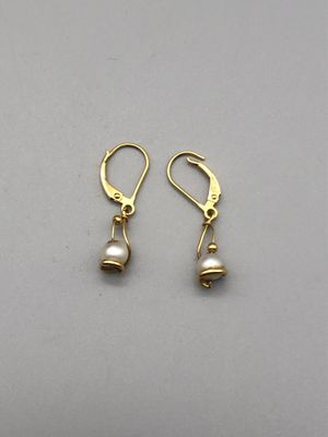 une paire de boucles d'oreilles en or et perles posées sur un fond gris