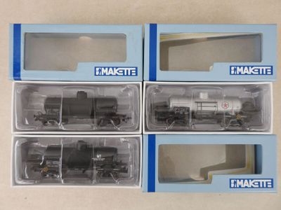 trois cartons contenant des trains miniatures posés sur une table