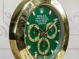 the rolex watch is green and gold on a wooden table