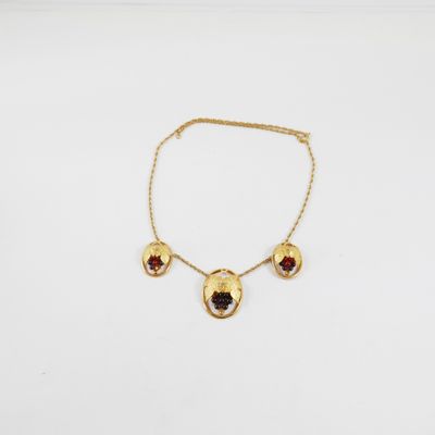 un collier en or orné de grenats sur fond blanc