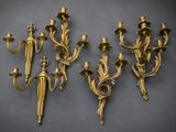 four antique brass wall sconces on a gray background