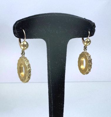 pair of gold tone earrings on a black display stand