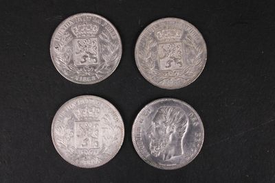 quatre pièces de monnaie britanniques différentes posées sur une surface noire, sur fond noir