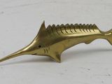 a brass fish figurine sitting on top of a white surface
