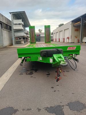 une remorque à plateau verte garée sur le bord de la route