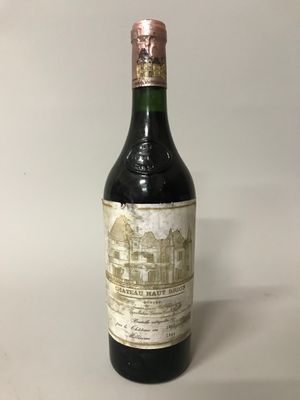 une vieille bouteille de vin posée sur une table blanche
