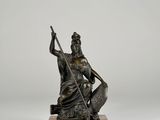 a bronze statue of a woman holding a spear and a fish
