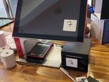 a desk with a monitor, keyboard, remote, and other items on it