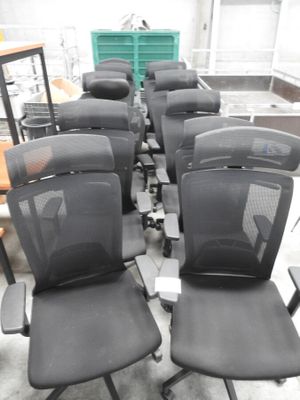 Plusieurs chaises de bureau noires sont alignées en rang dans une pièce