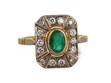 gros plan d'une bague en émeraude et diamant sur fond blanc