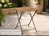 une petite table en bois posée sur une terrasse, à côté d'une plante en pot