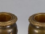 two gold vases sitting next to each other on a table