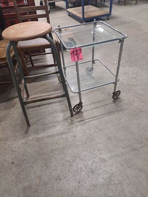 une table en verre sur laquelle est posé un tabouret, dans un entrepôt