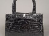 a black crocodile skin handbag on a white background