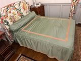 a bed with a green comforter on it in a room