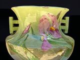 un vase vert orné de fleurs violettes, posé sur un fond noir